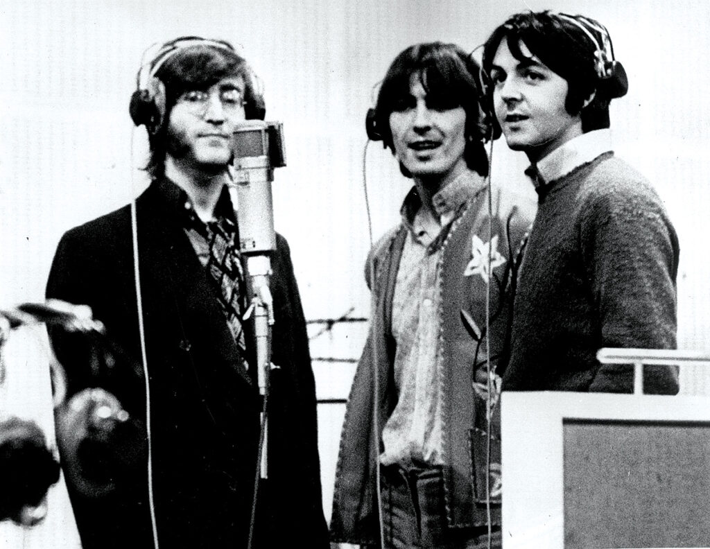 Photo of John Lennon, George Harrison, and Paul McCartney of the Beatles around a Neumann U47 microphone