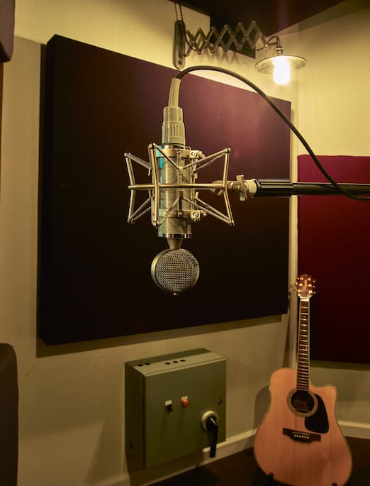 Photo of a Neumann CVM microphone and an acoustic guitar in an isolation booth at Morrisound Recording