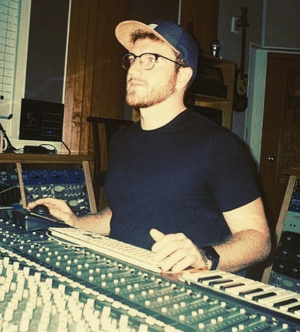 Andrew Boullianne sitting in front of an audio mixing console.